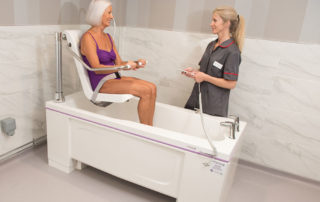 Woman in electric chair bath with carer